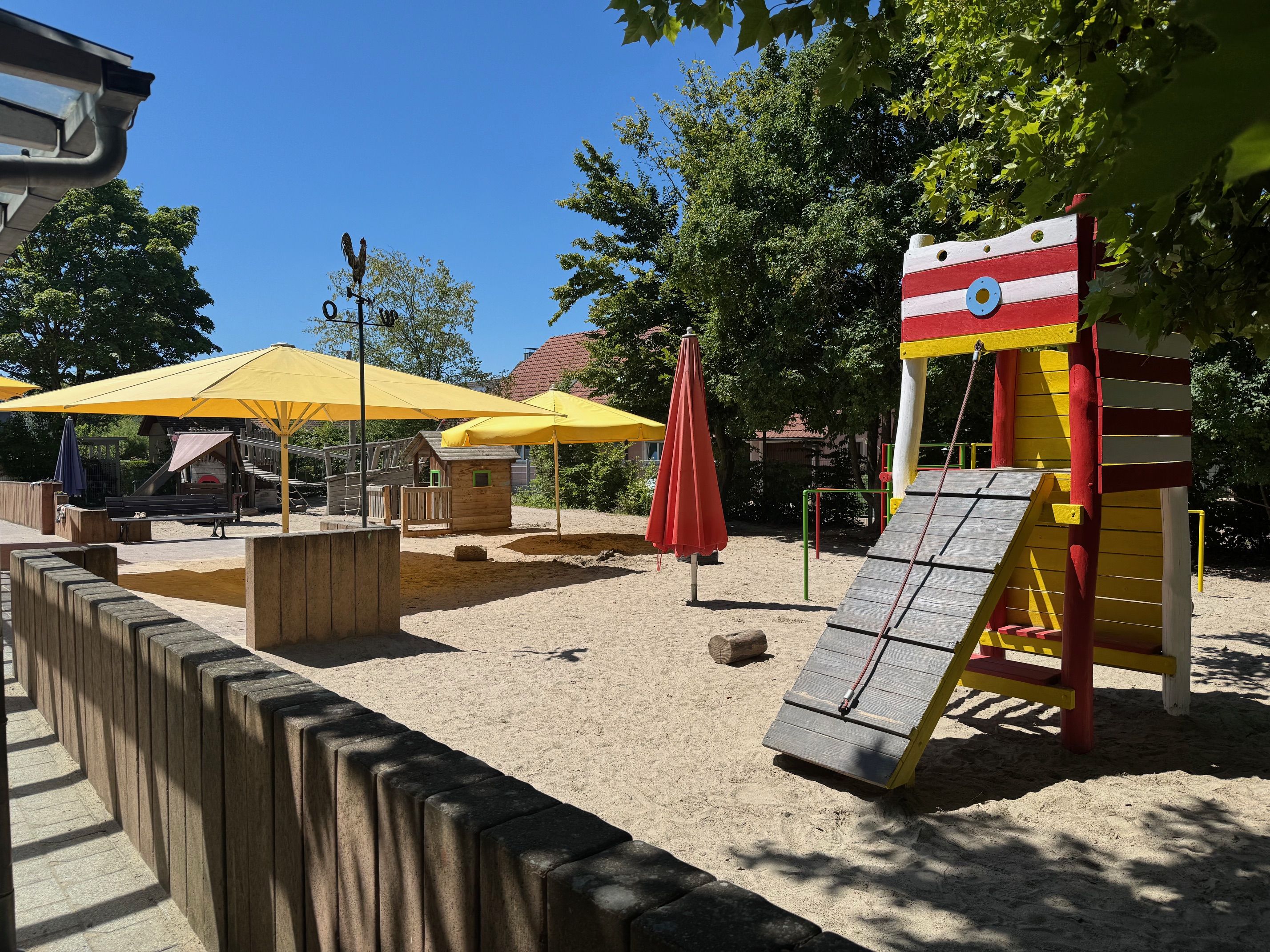 Außengelände Kita, Sandkasten mit Spielturm und Sonnenschirmen